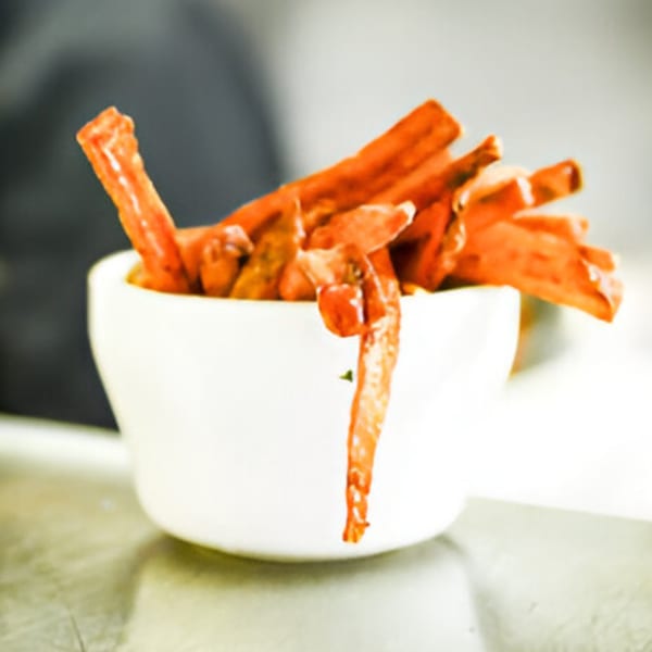 A white bowl filled with crispy, orange-red sweet potato fries from Jewlz Bar.