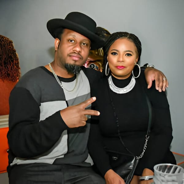 A man in a black hat and a woman with braids pose together at Jewlz Bar.